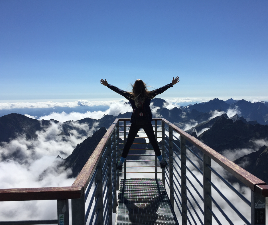 mulher admirando a paisagem feliz com os braços abertos