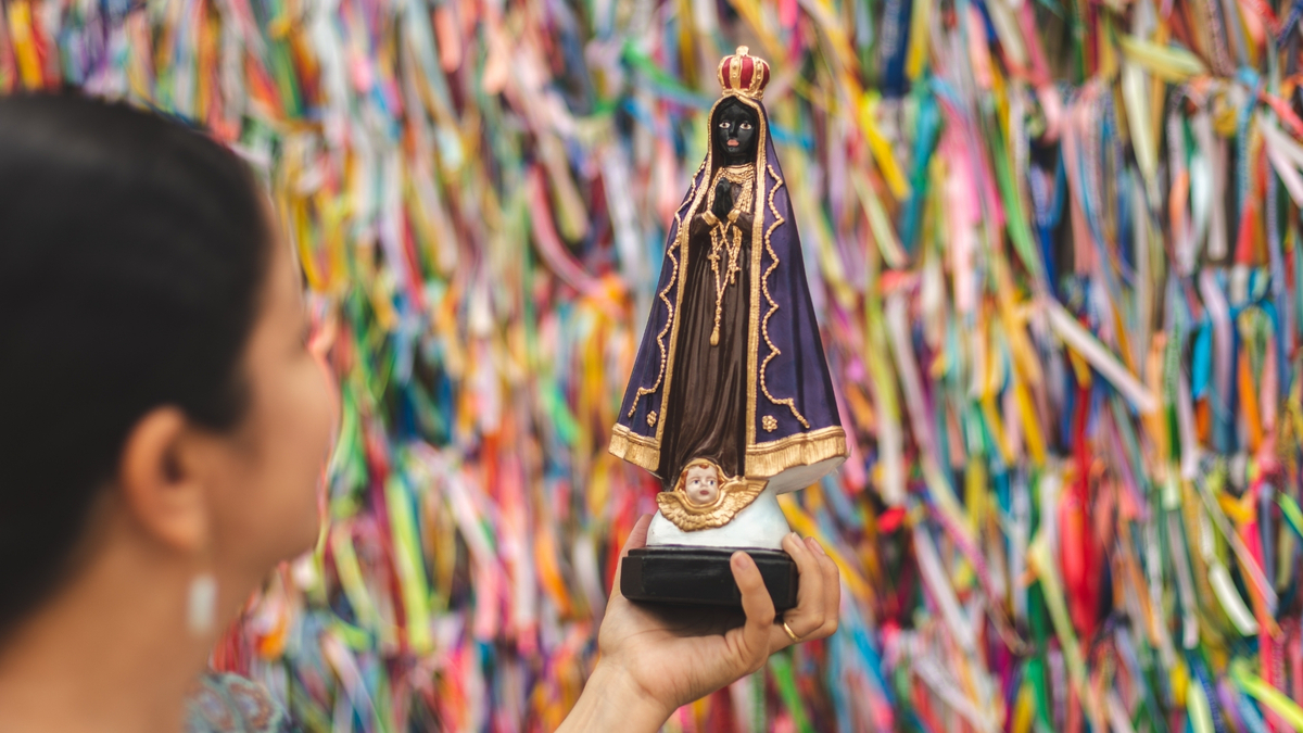 Mulher segurando imagem de Nossa Senhora Aparecida.