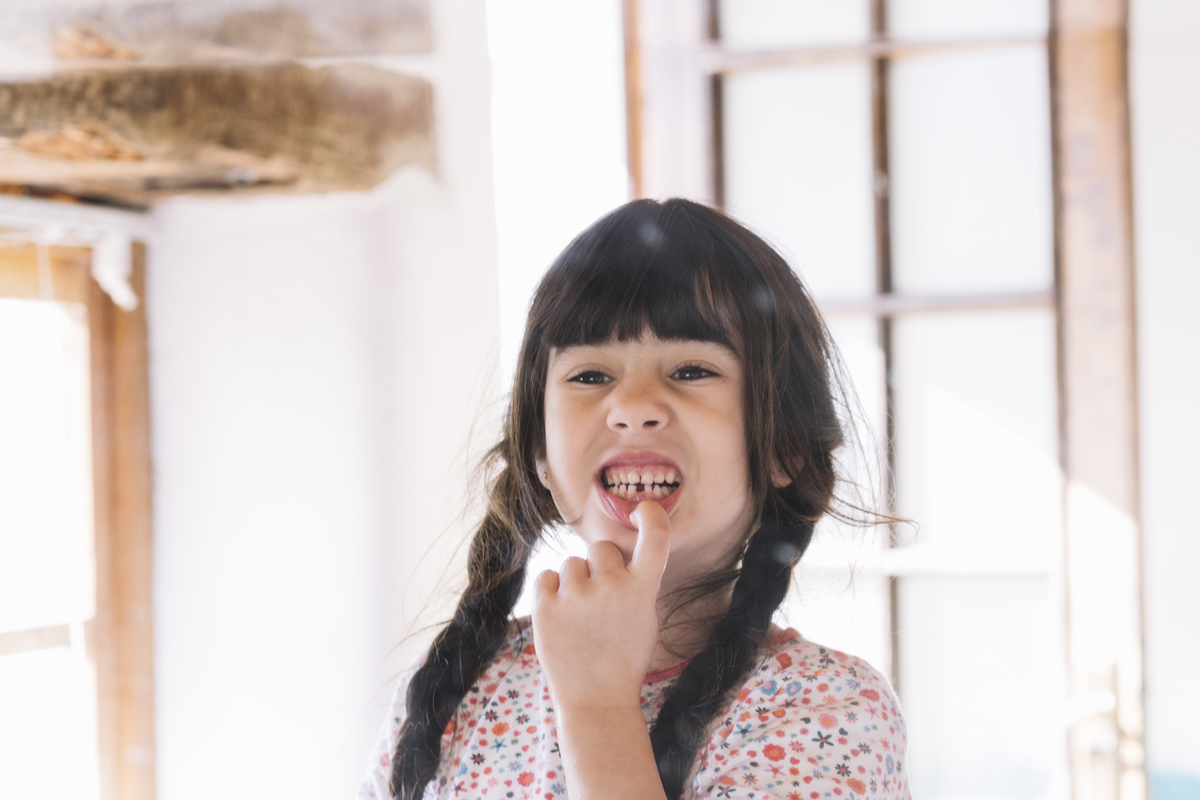 Menina com dente da frente quebrado