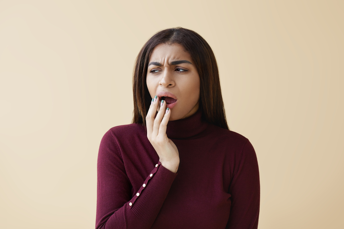 Mulher percebendo que está com dente quebrado