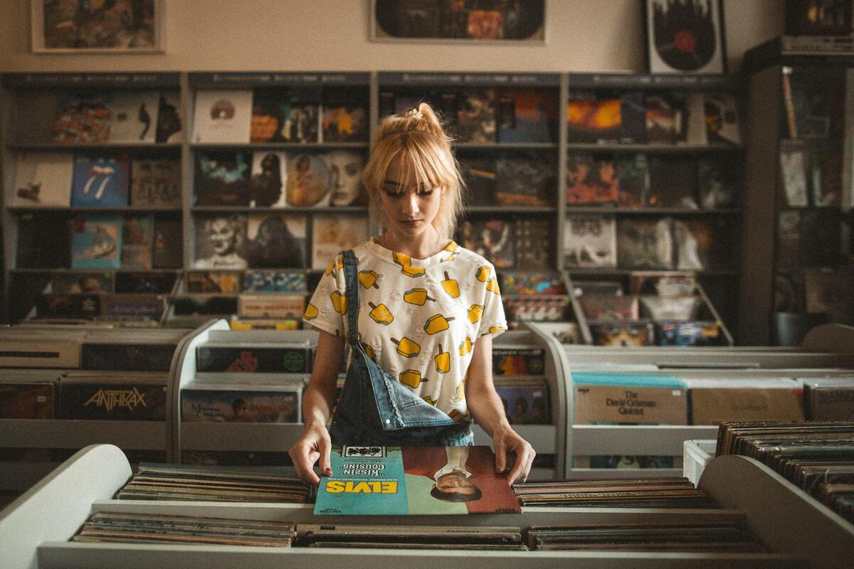 Menina escolhendo vinil em uma loja.