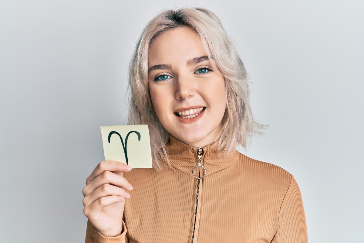 Mulher sorridente segurando símbolo do signo de Áries