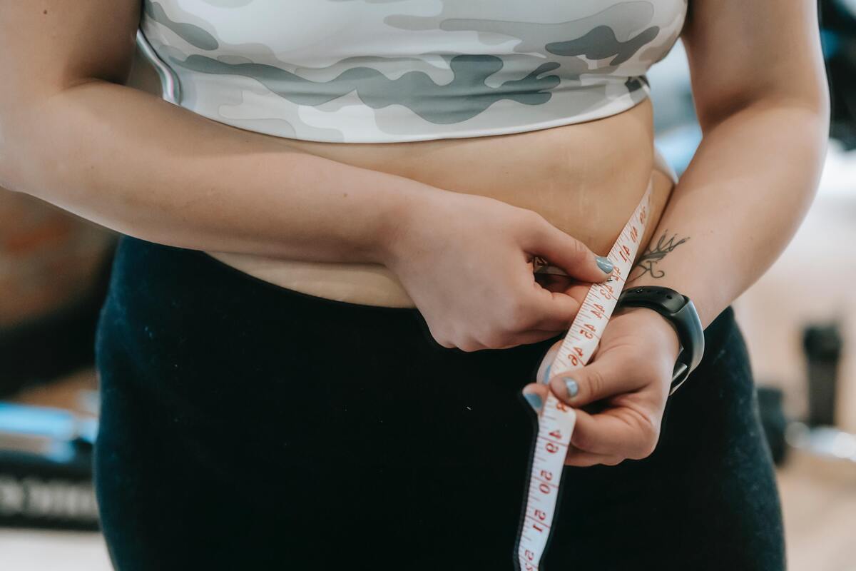 Mulher medindo cintura com fita métrica