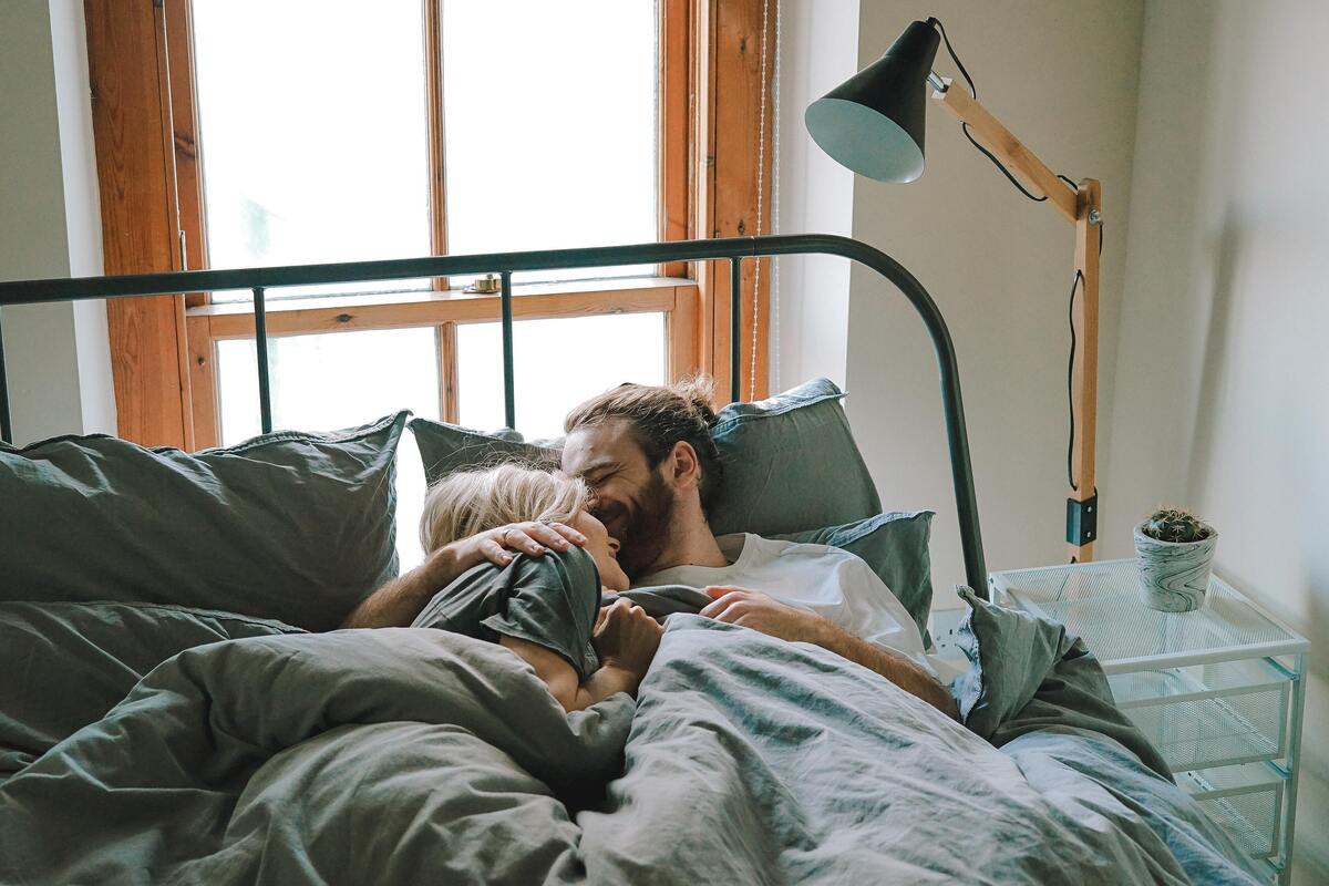 Casal se abraçando na cama.