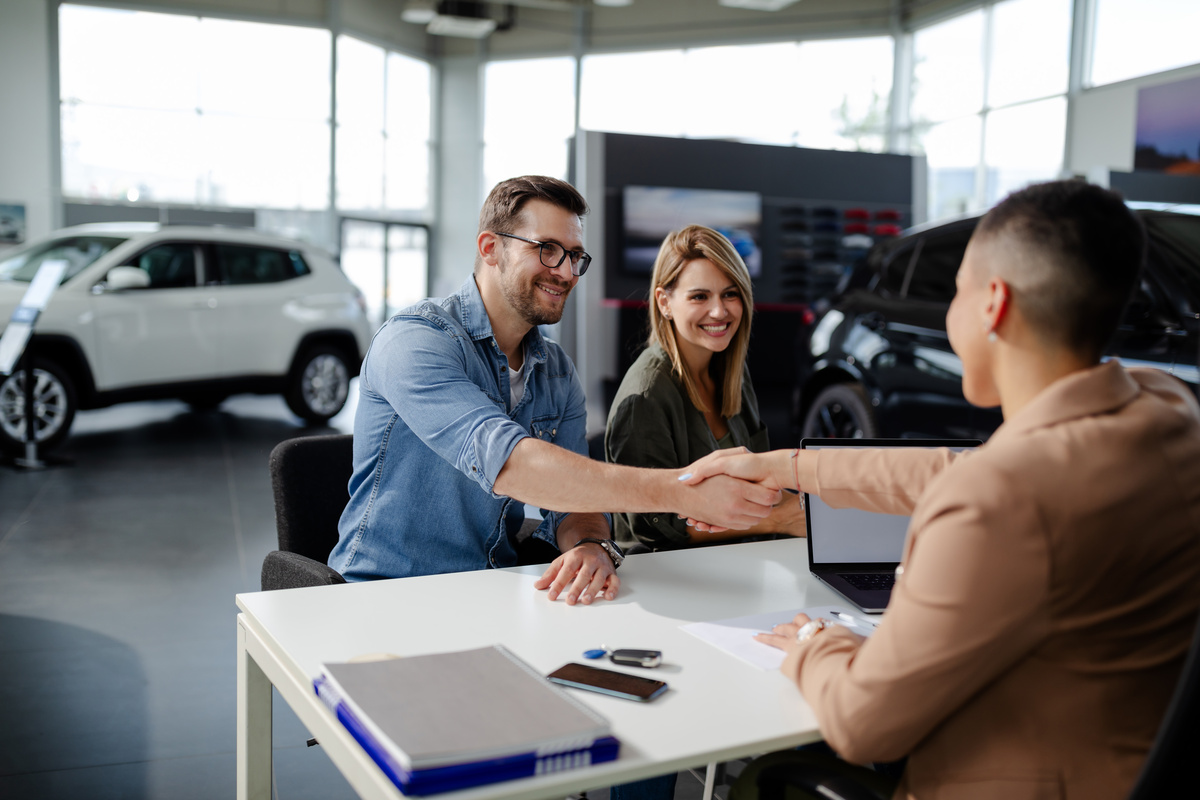 Vendedor apertando a mão de cliente que acabou de comprar carro