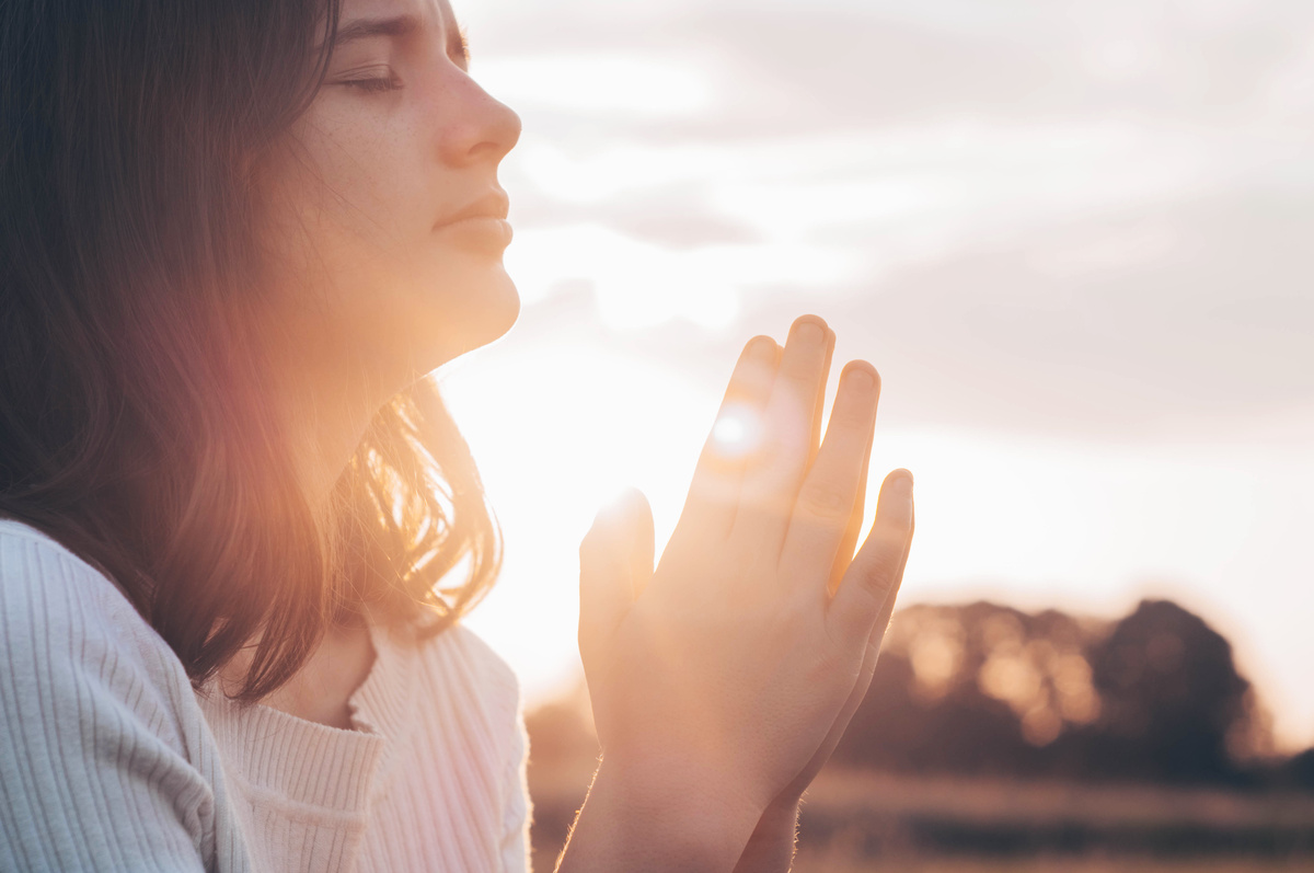 Mulher rezando na luz do Sol