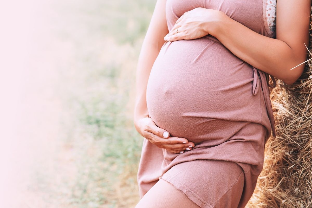 mulher grávida com as mãos sob a barriga