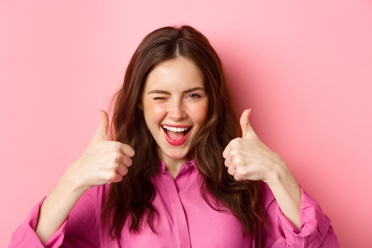 mulher sorrindo, fazendo elogios e sinal de positivo com as mãos