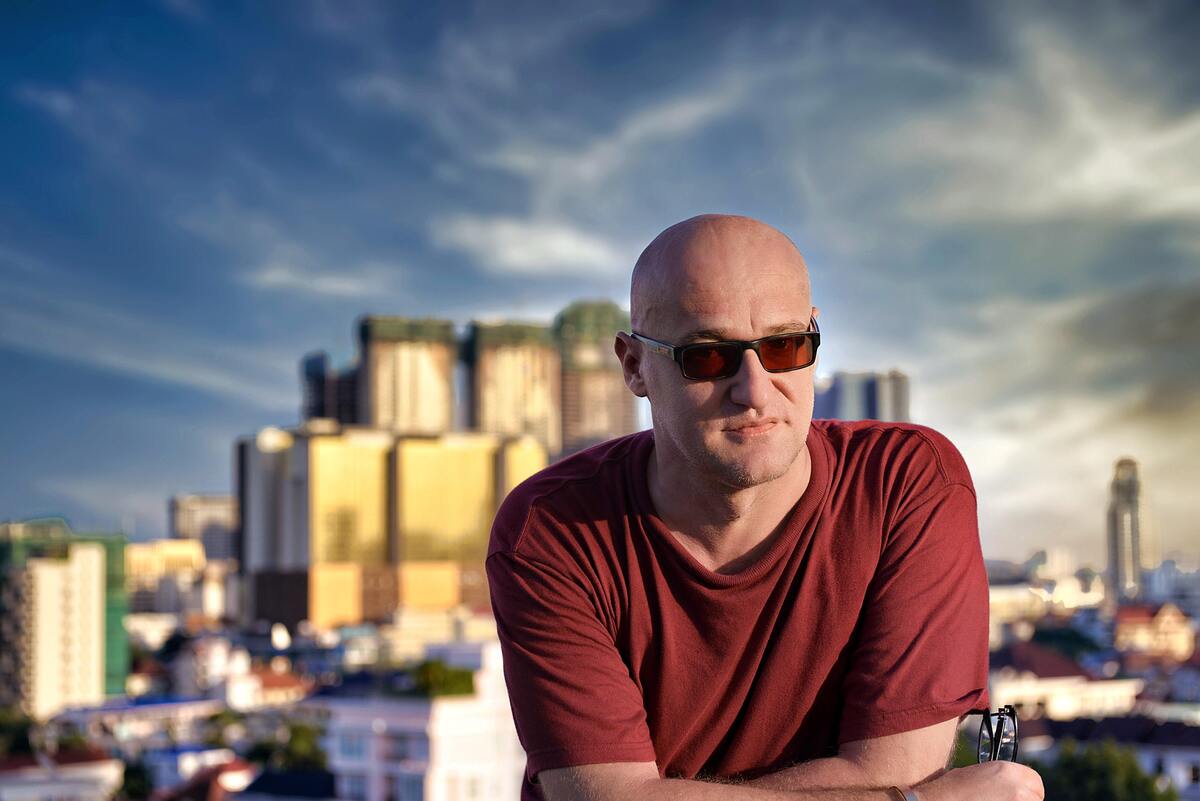 Homem careca em frente a uma paisagem de prédios.