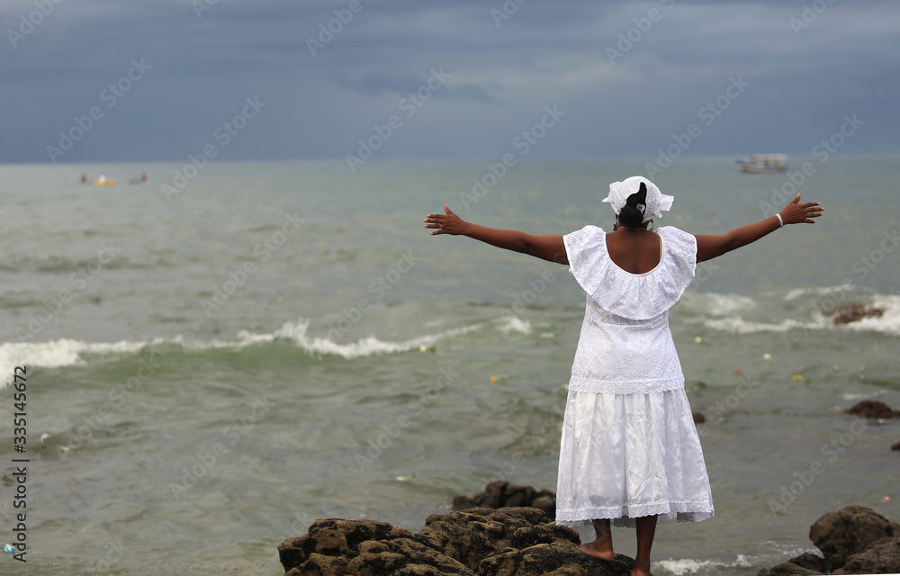 Mulher de braços erguidos sobre o mar