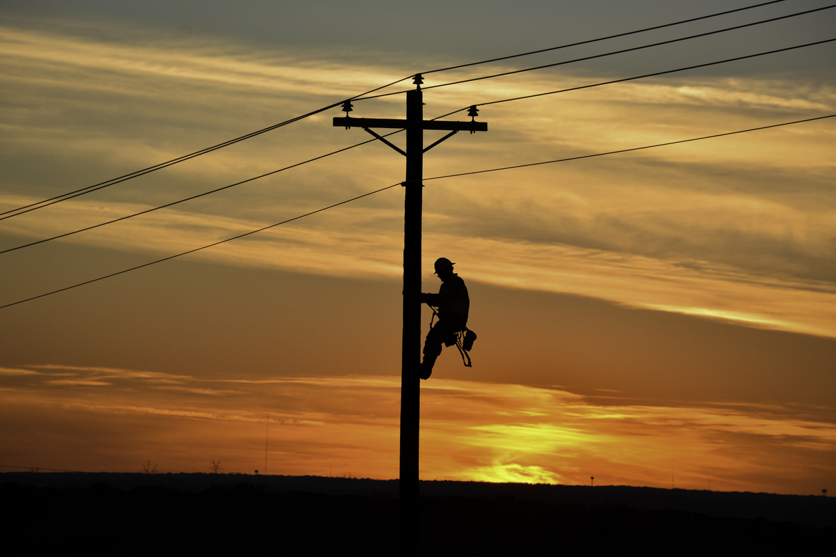 Homem com equipamentos subindo em um poste de energia