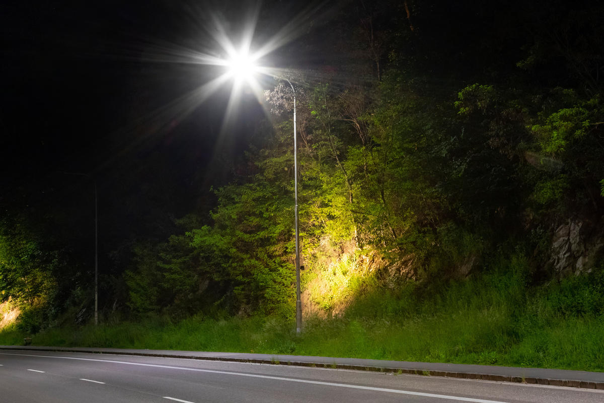 Poste de luz iluminando rua a noite