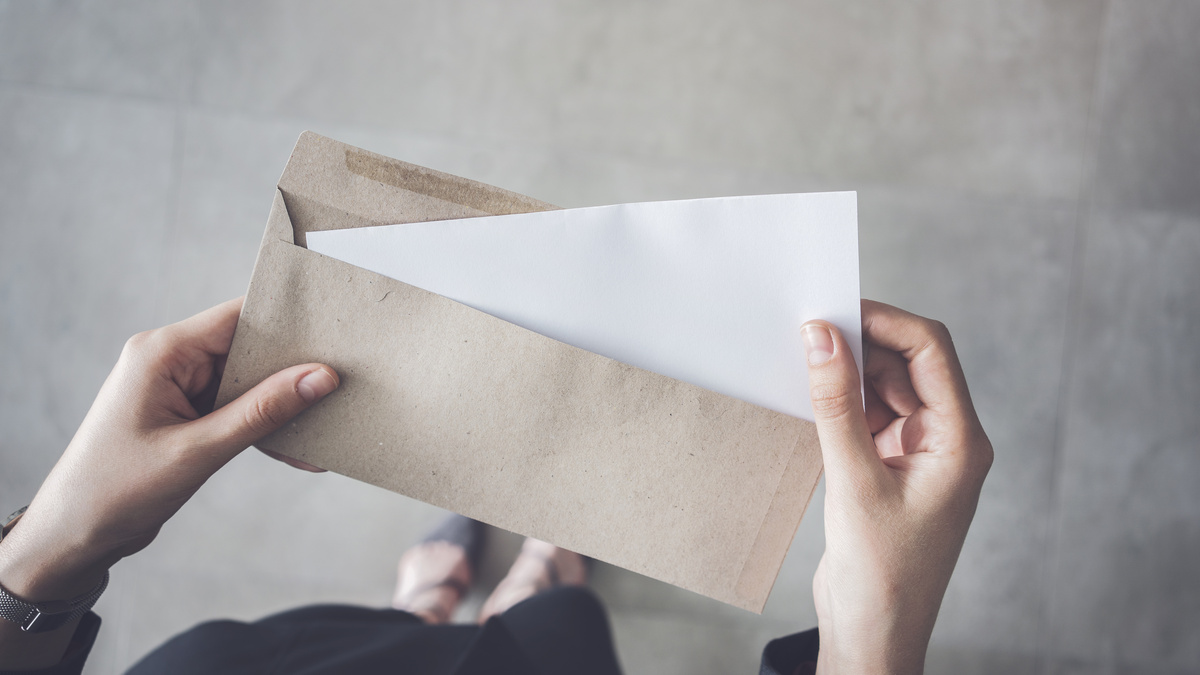 Mãos femininas tirando papel de dentro de envelope