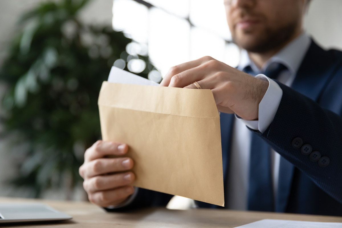 Homem retirando papel de dentro de envelope