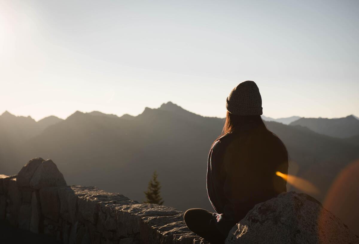 Mulher meditando no topo de uma montanha.