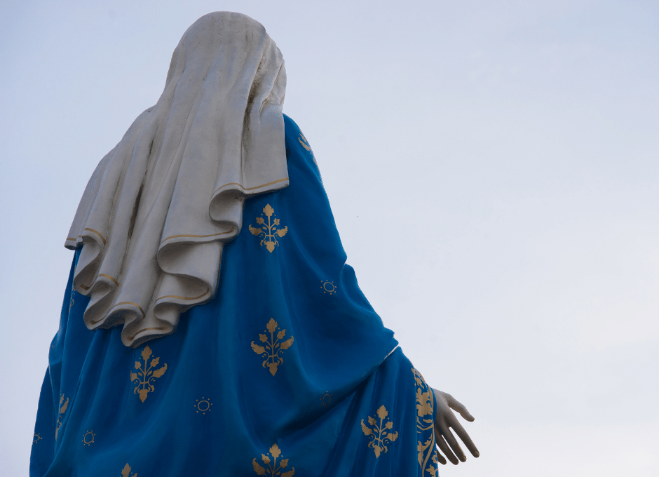 Estátua da Virgem Maria de costas olhando para frente e o céu acima