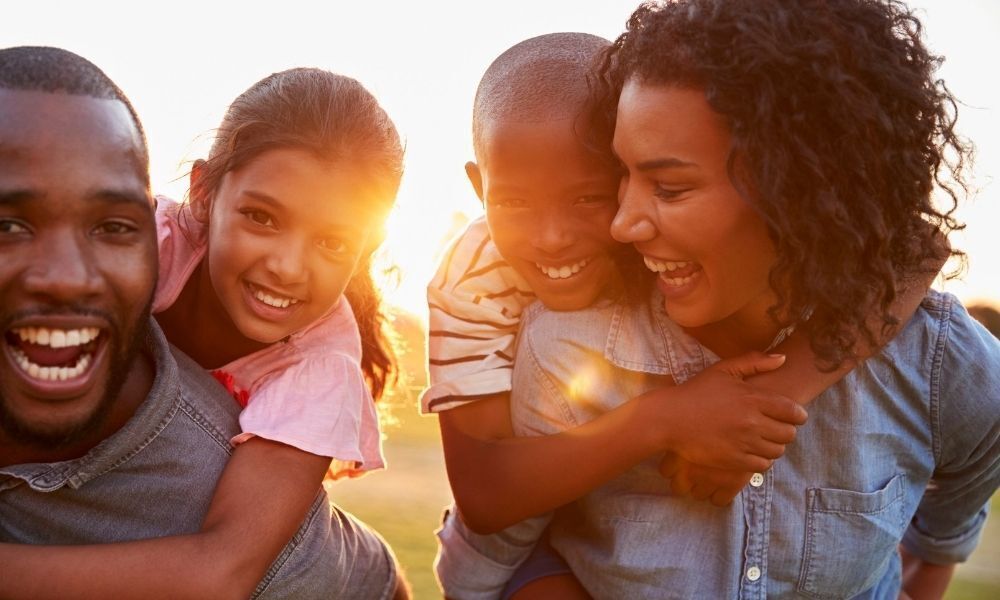 Pai, mãe e filhos sorridentes caminhando.