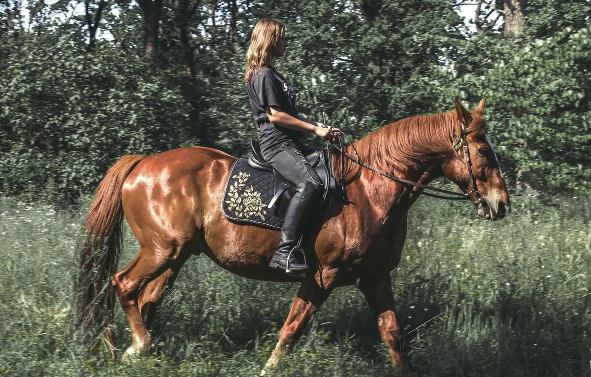 Mulher andando a cavalo.