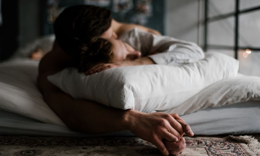 Casal abraçado na cama.