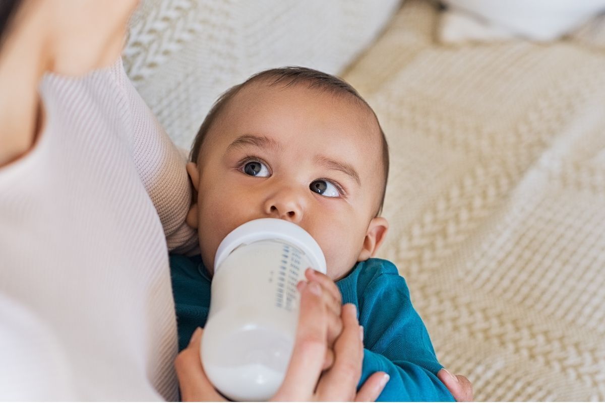 Mãe alimentando o filho no colo com uma mamadeira