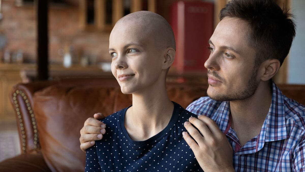 Homem abraçando uma mulher careca.