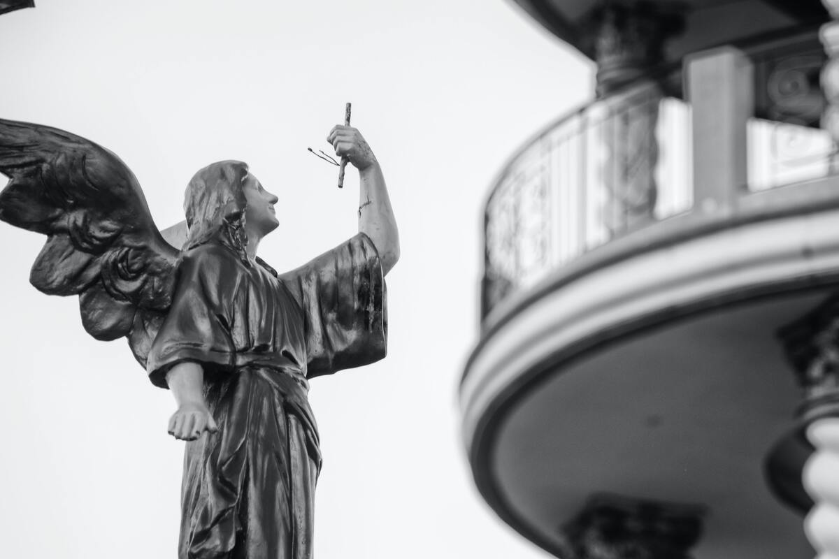 Estátua de anjo apontando com o rosto voltado para o céu. 