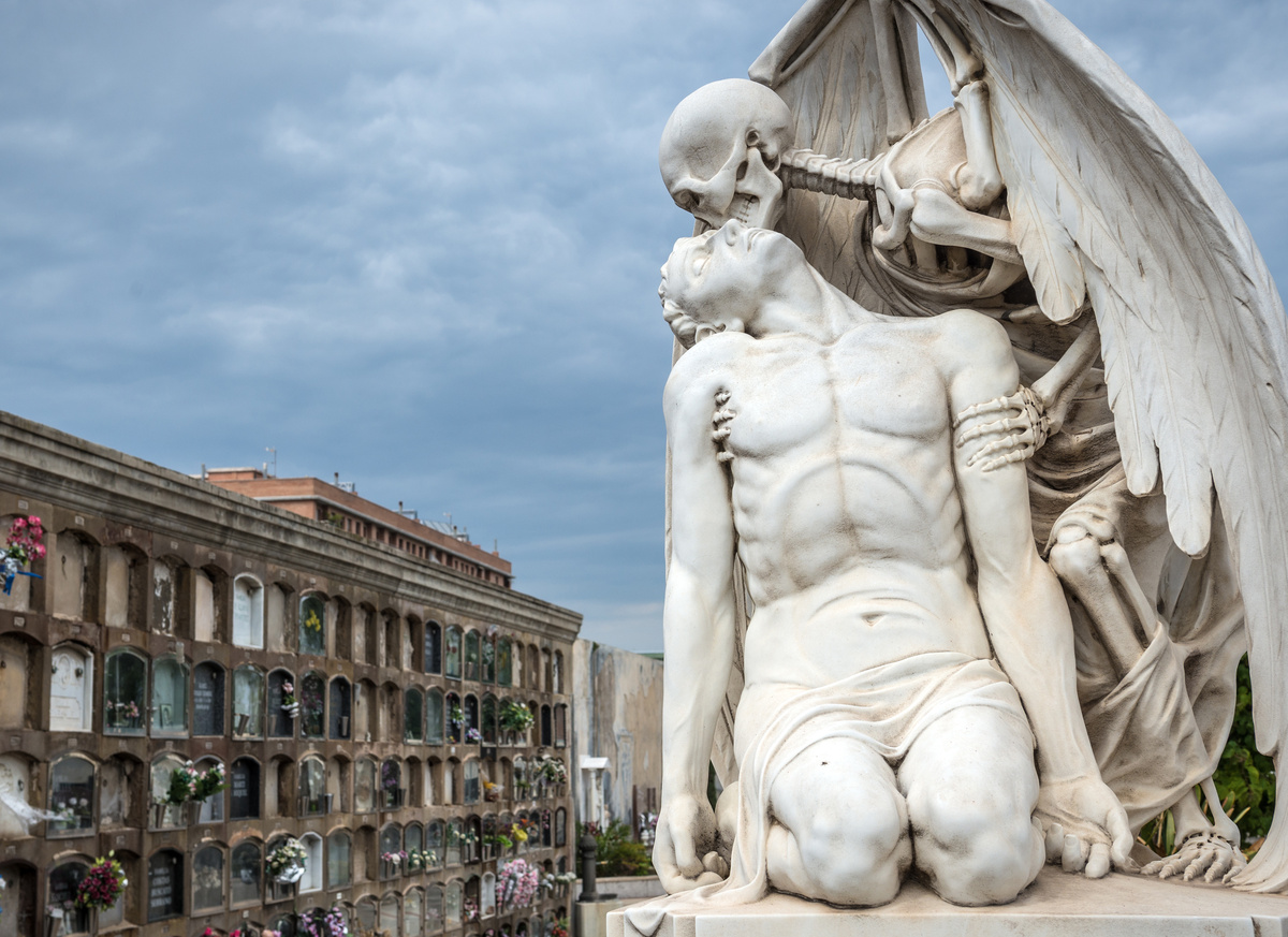 Estátua de anjo da morte beijando pessoa ajoelhada.