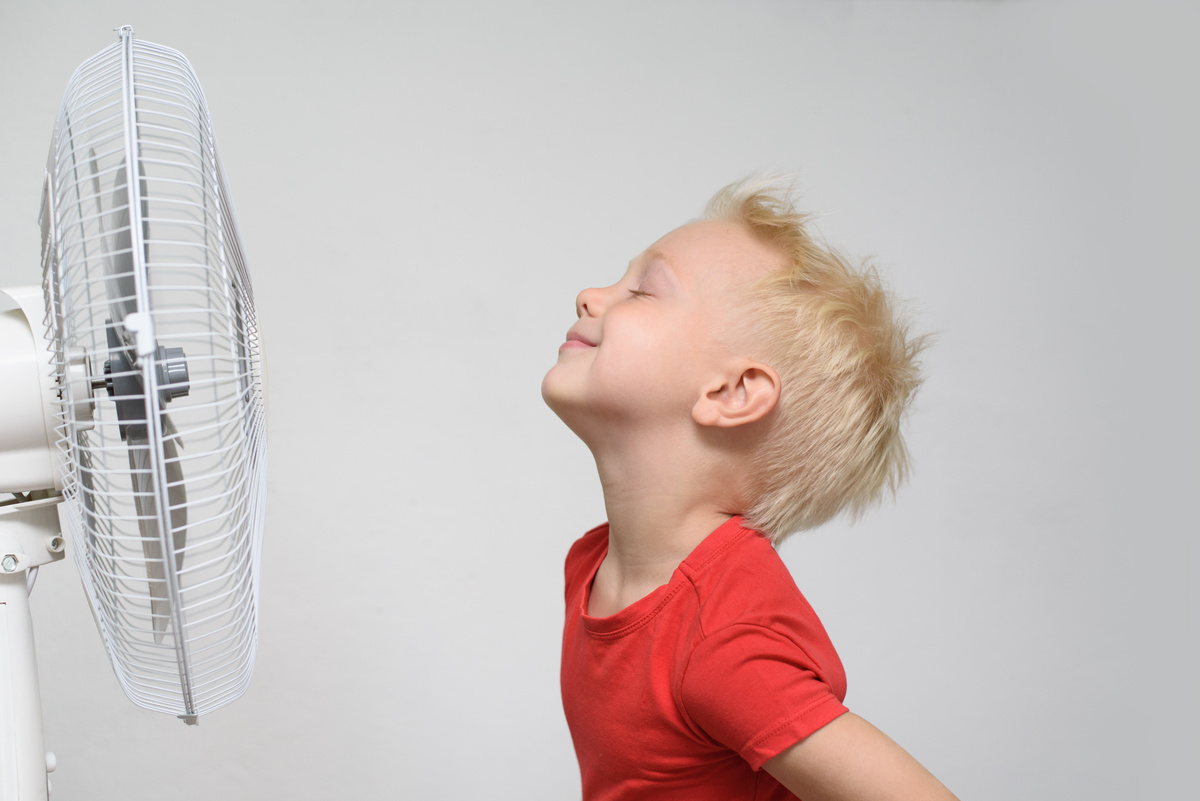 Menino sentindo o vento do ventilador