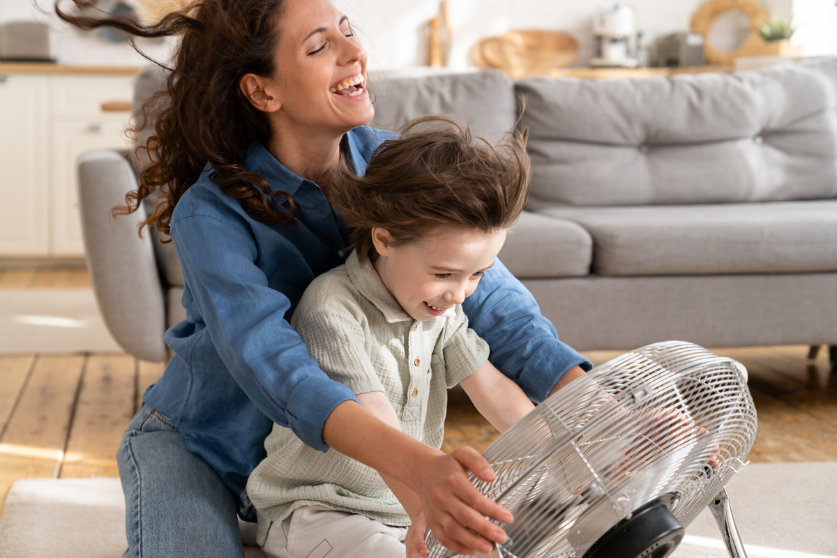 Mãe e filho brincando com o vento do ventilador