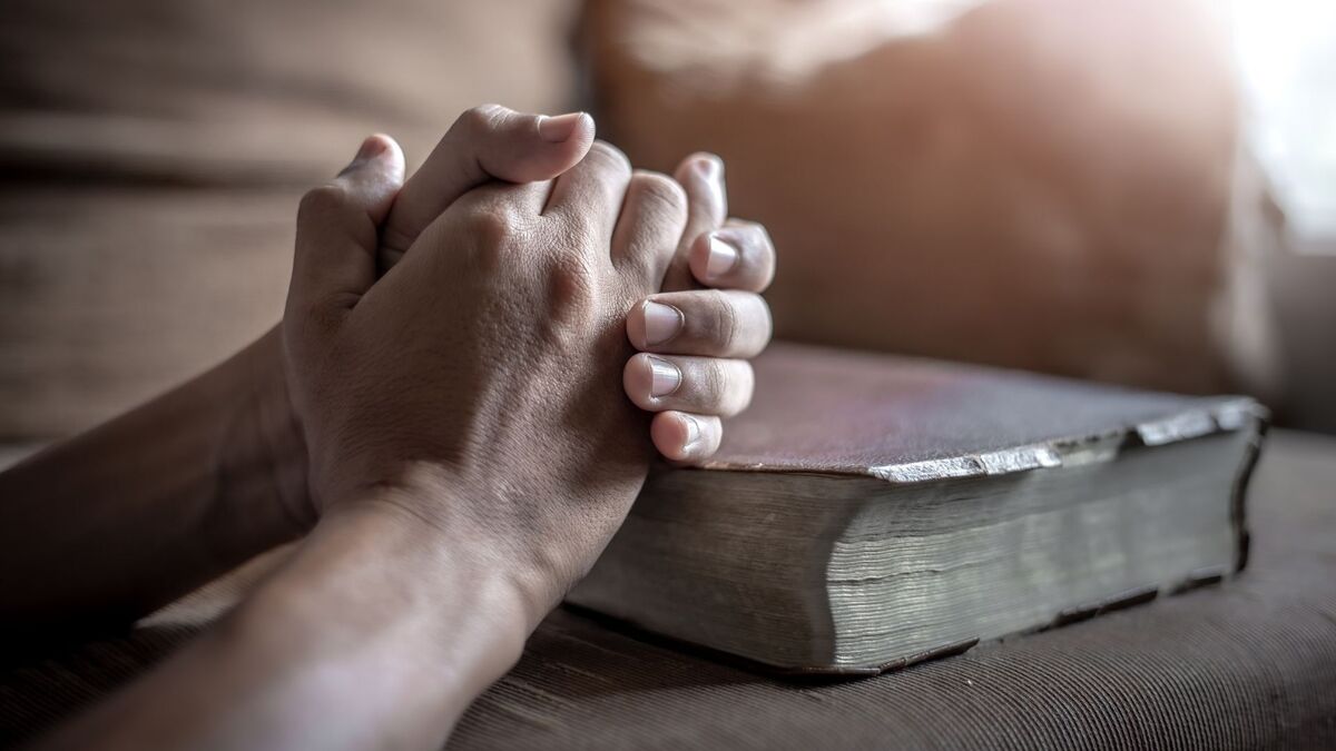 Mãos e uma bíblia.