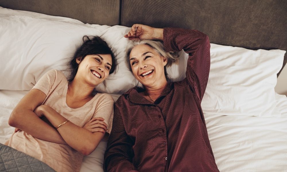 Mãe e filha deitadas e sorrindo.