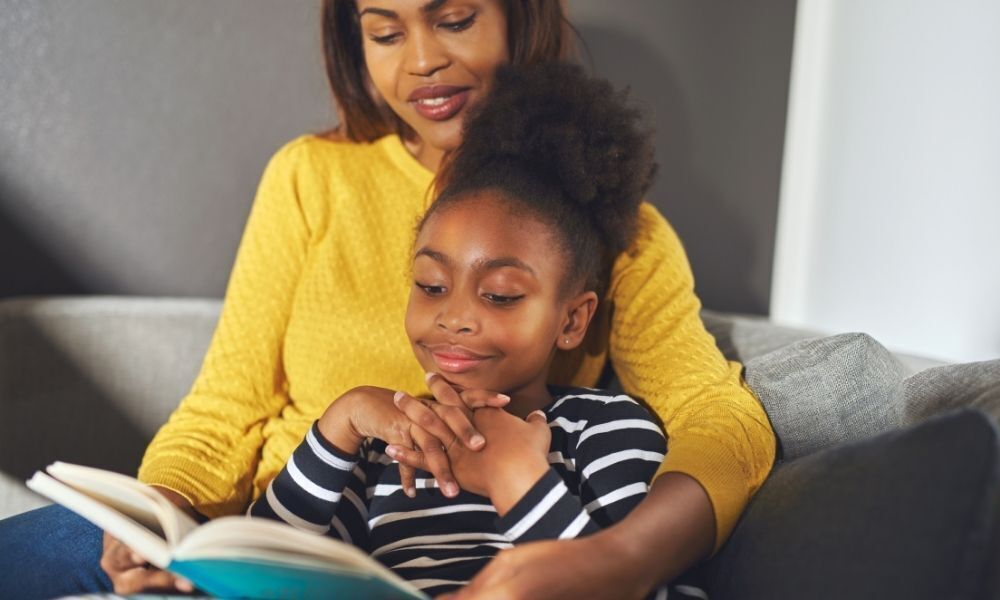 Mãe e filha criança lendo livro.