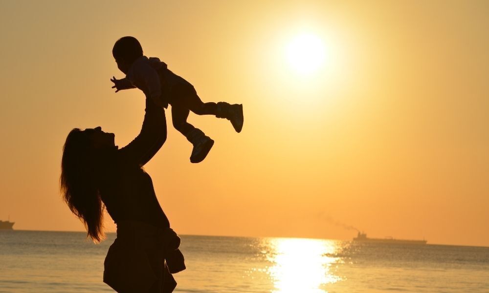 Mãe carregando filho no colo.