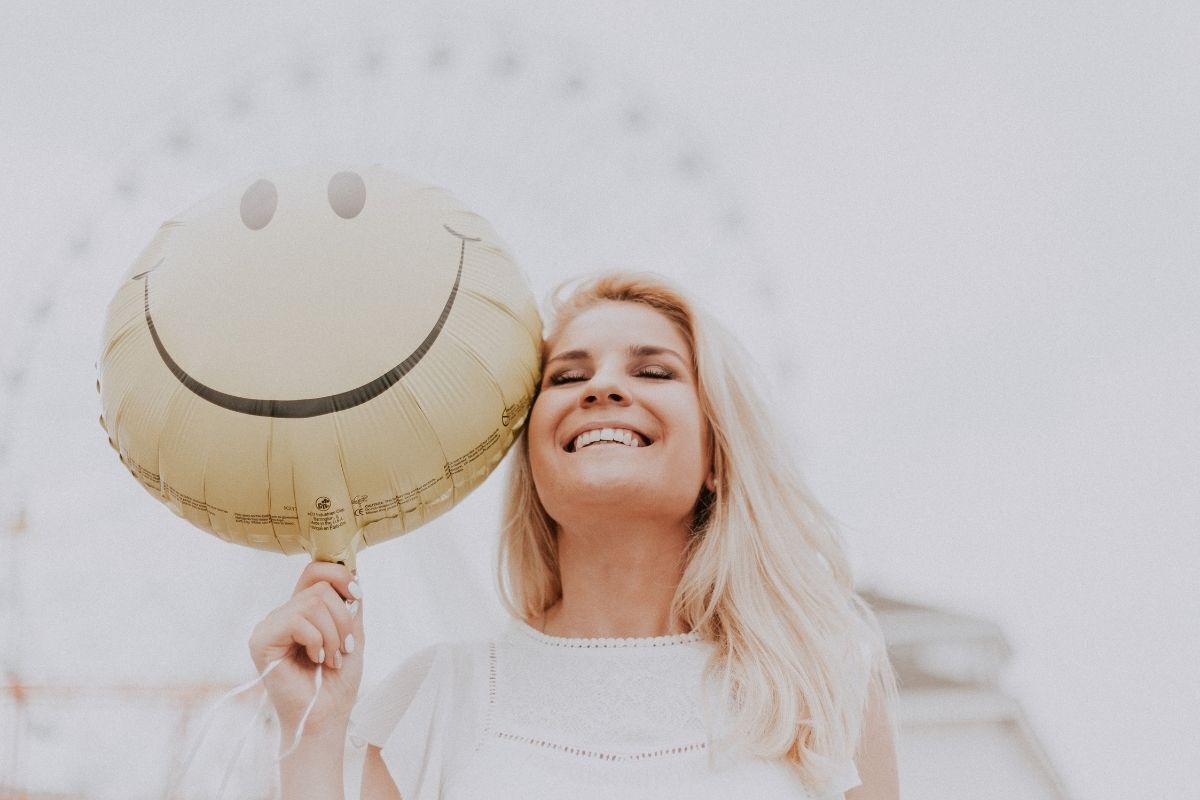 Mulher sorrindo com balão feliz.