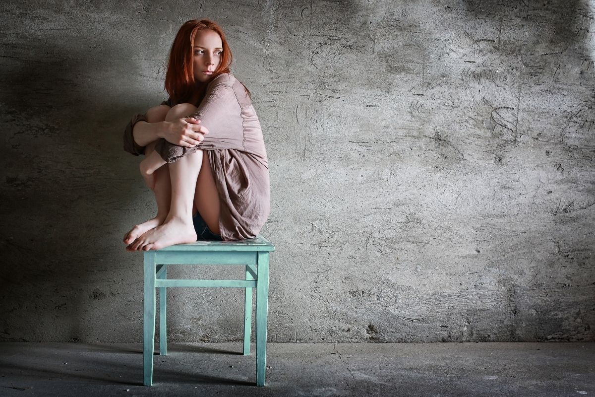 Mulher isolada, sentada em uma cadeira, triste