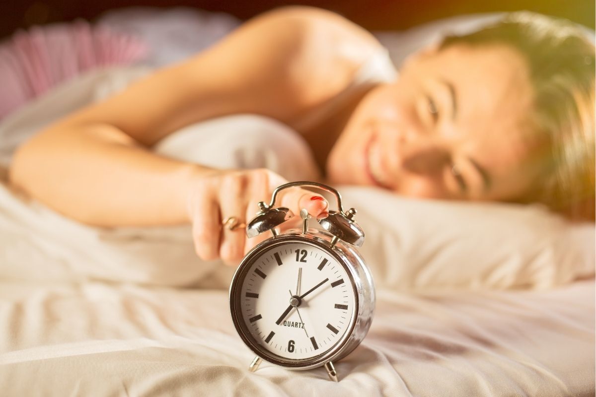 Mulher acordando feliz, desligando o relógio despertador