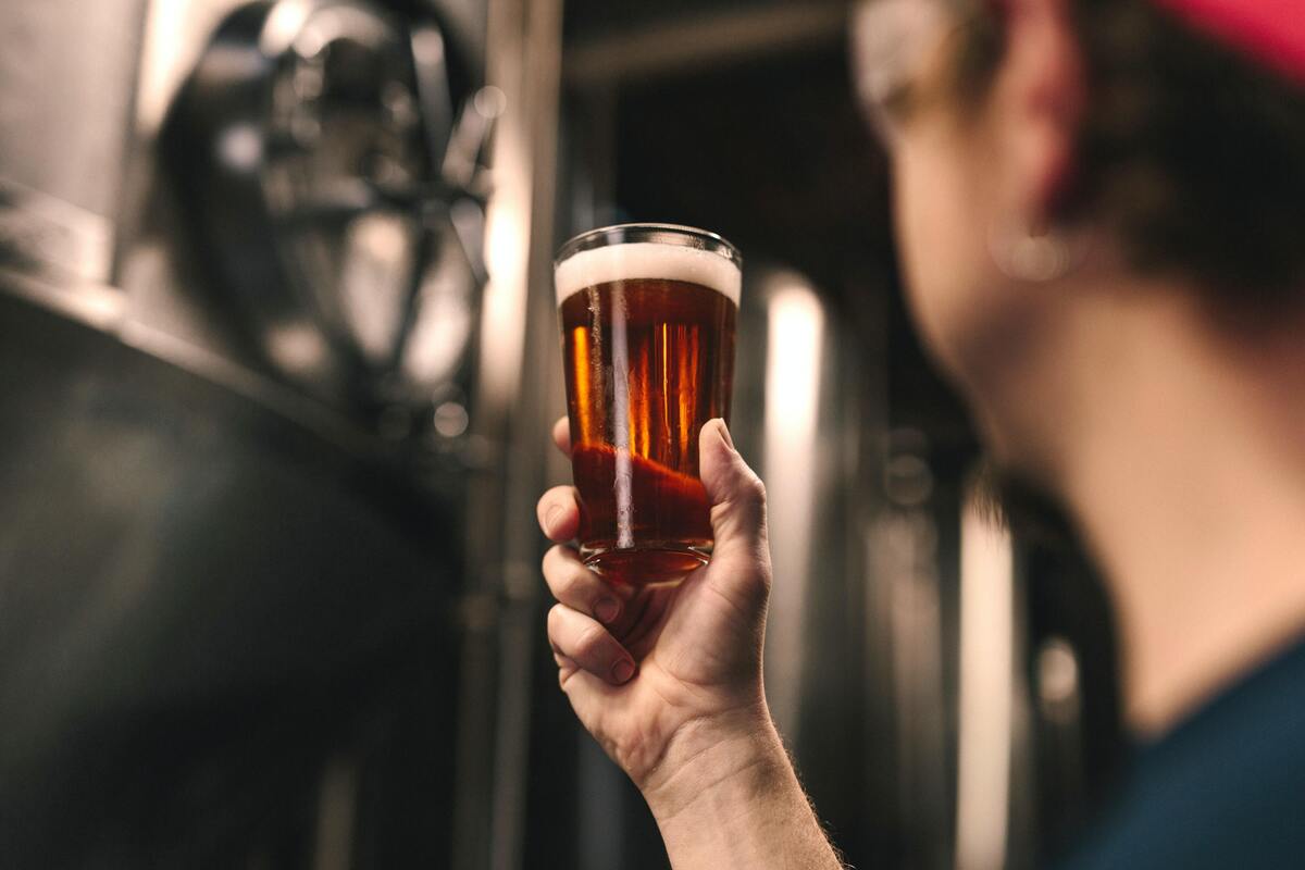 Homem segurando copo de cerveja.