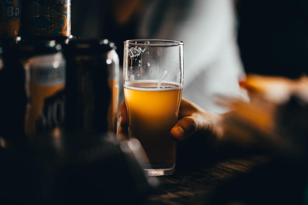 Homem segurando copo de cerveja.