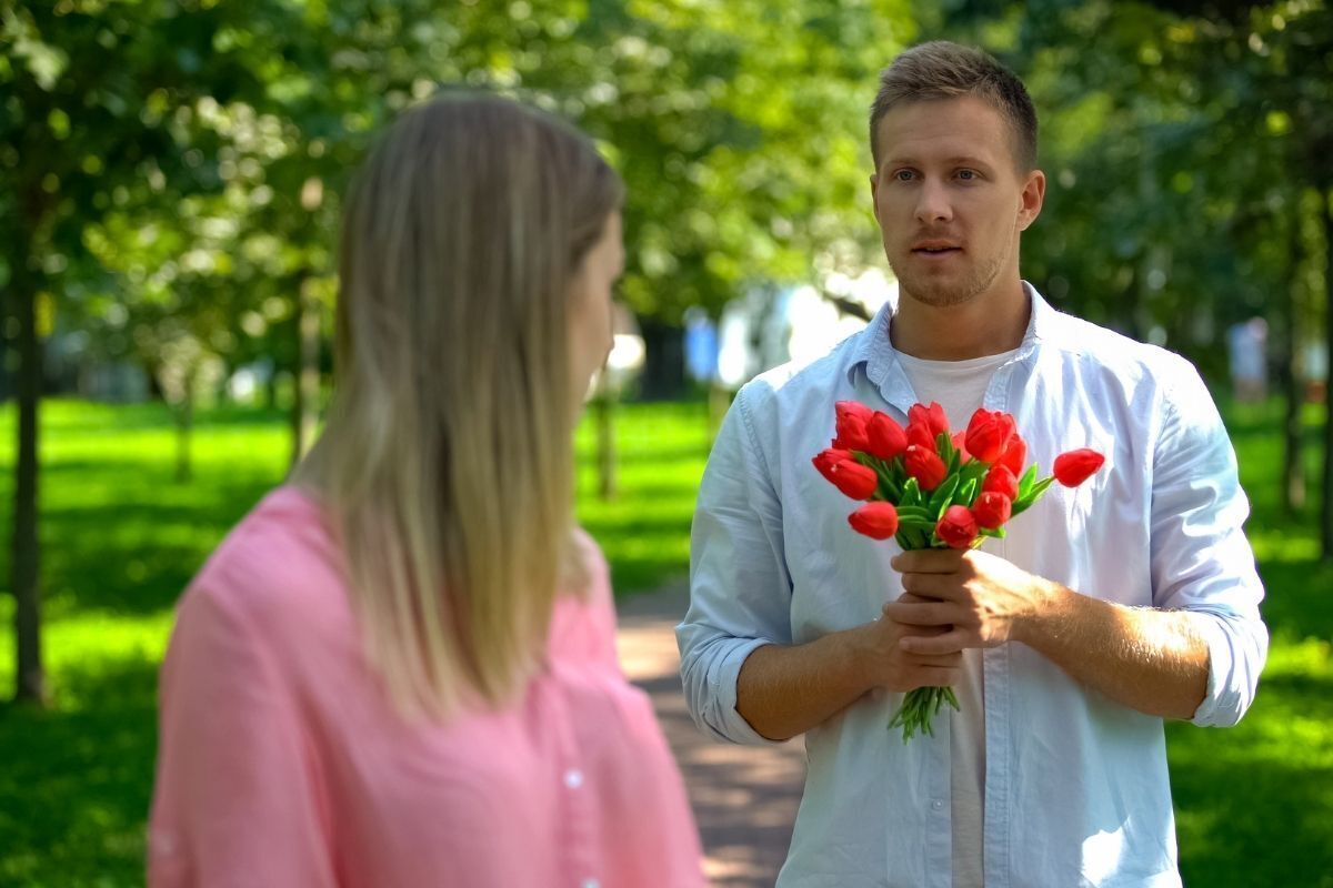 Mulher olhando para homem com buquê de rosas 