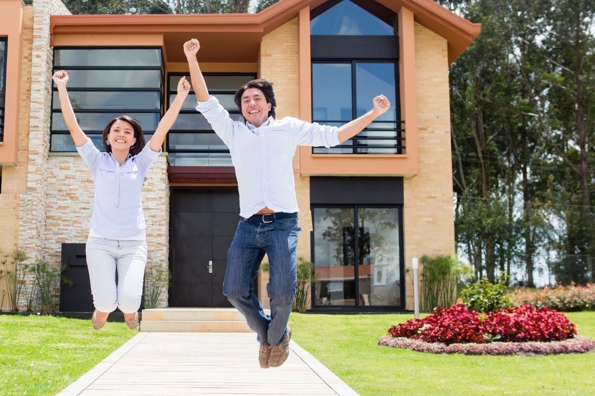 Casal saltitante e sorridente após comprar uma casa nova