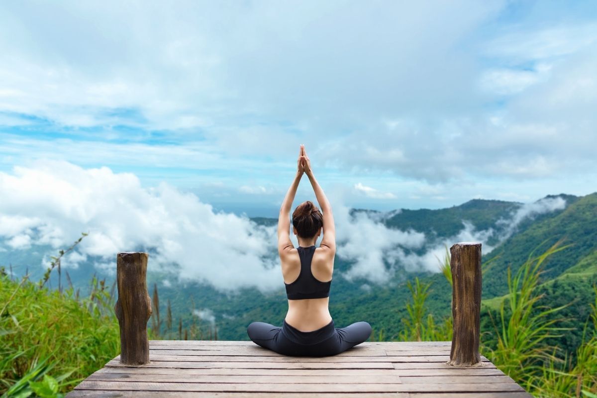 Mulher de costas, meditando em uma montanha