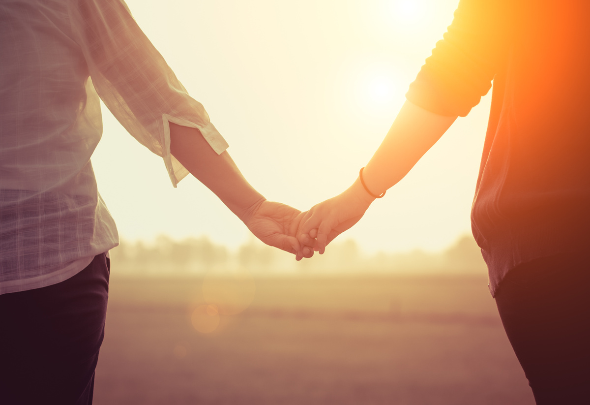 Casal dando as mãos ao pôr do sol