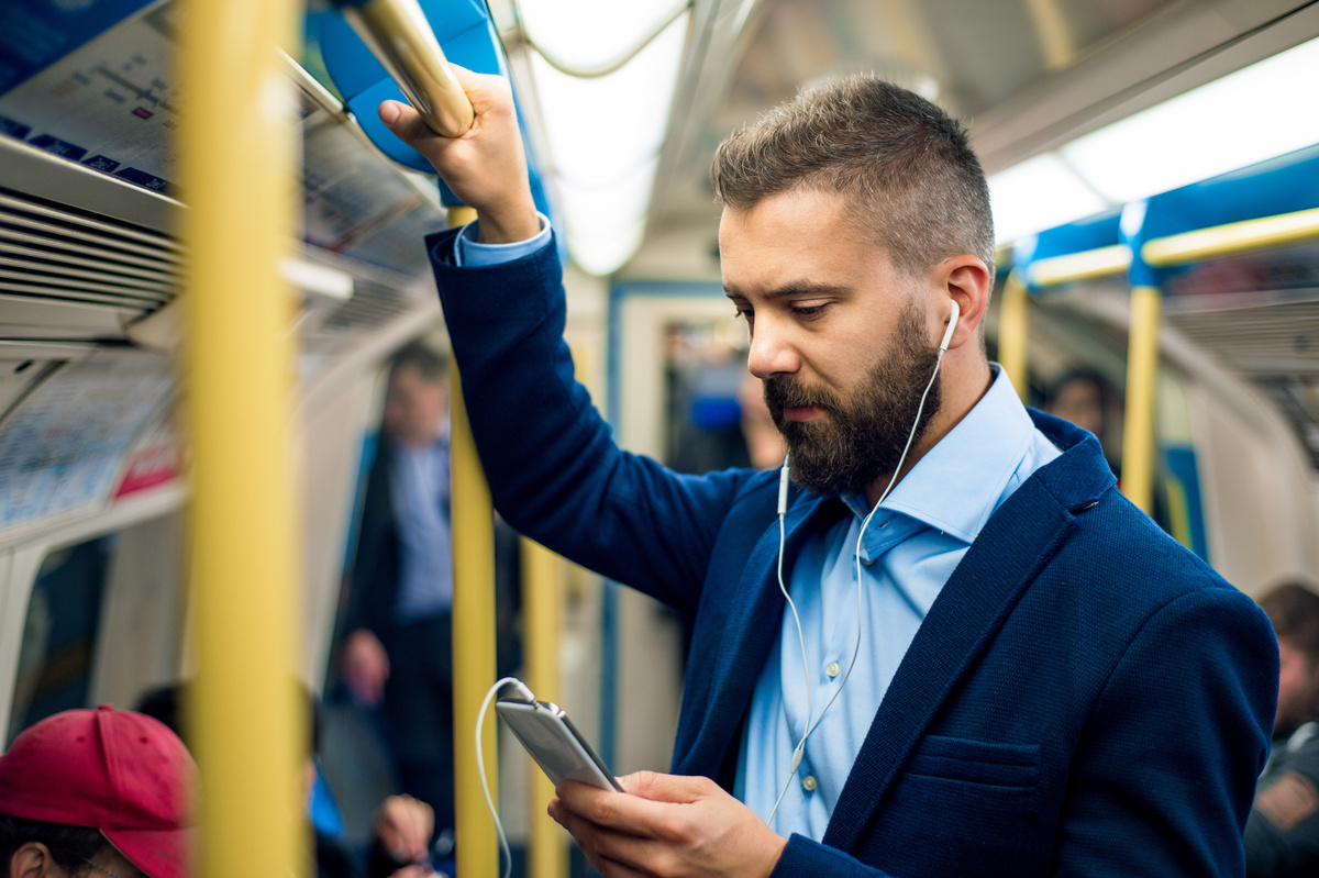 Homem mandando mensagem no metrô.