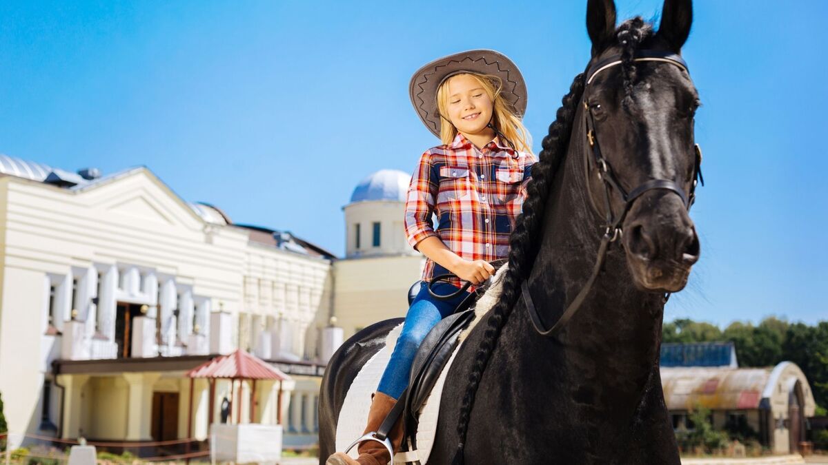 Cavalo manso com menina em cima.