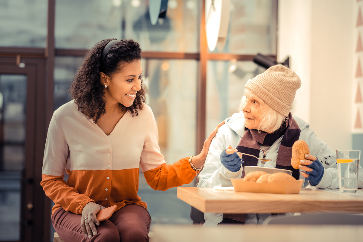 Mulher conversando com senhora em cafeteria