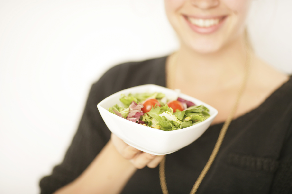 Mulher segurando pote com salada