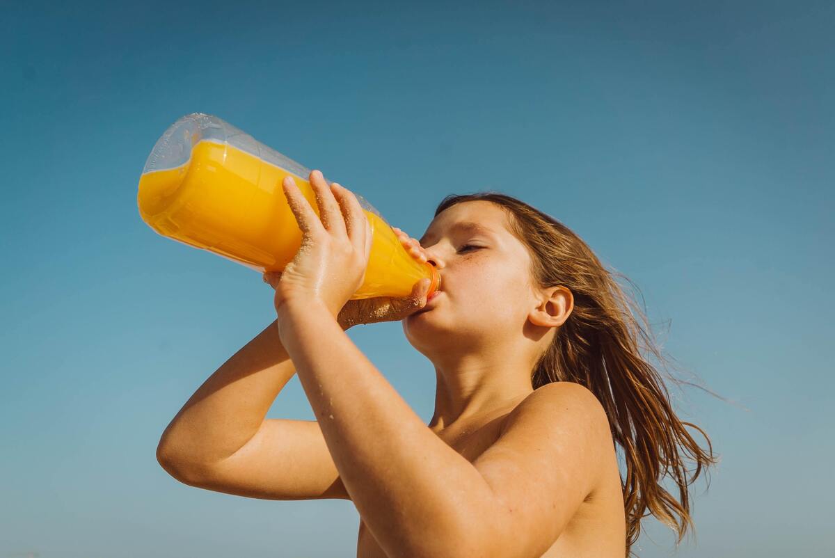 Menina bebendo garrafa de suco.