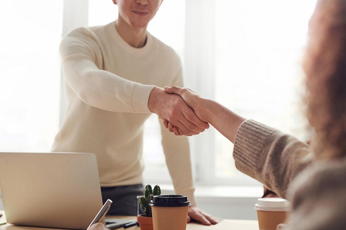 Homem cumprimentando a contratante no novo emprego