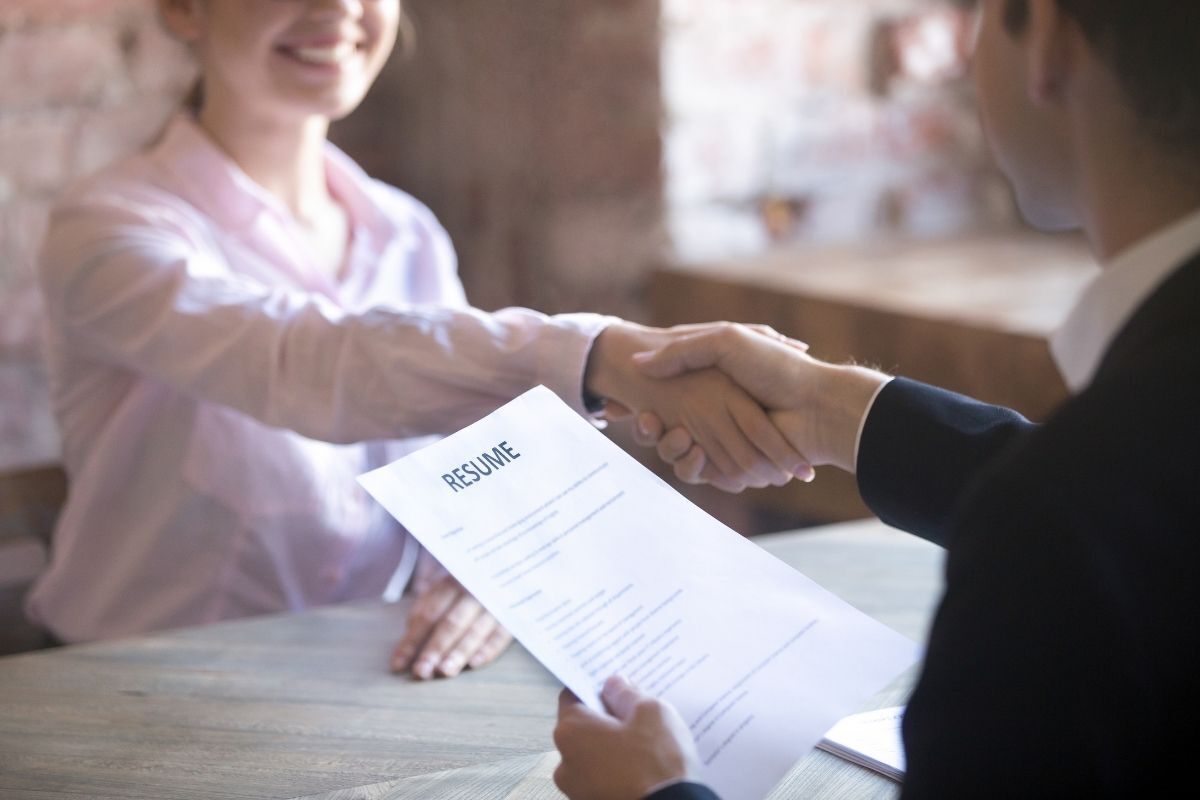 Mulher cumprimentando a contratante com um sorriso após assinar o contrato