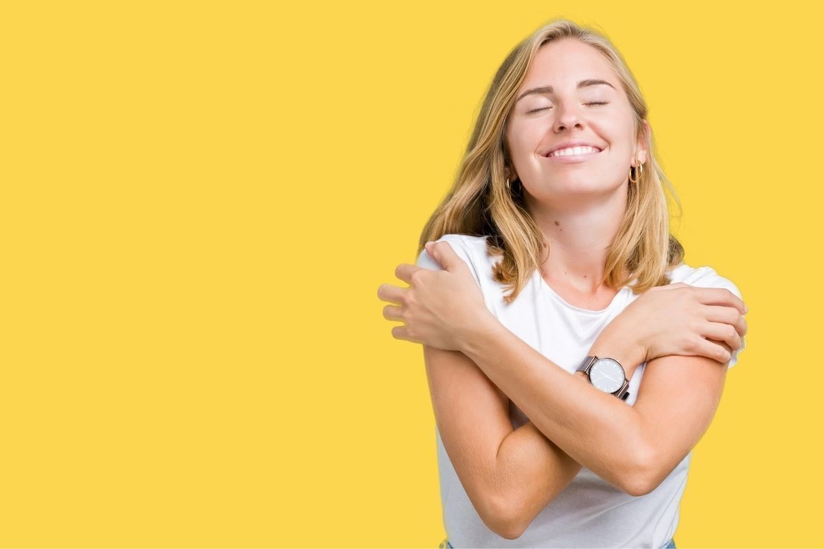 Mulher sorrindo e se abraçando 